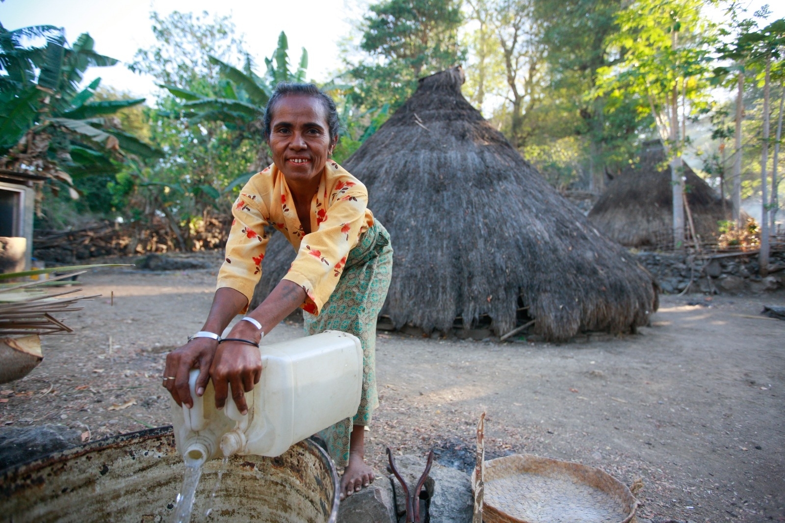 En kvinne henter vann utenfor huset sitt i Øst-Timor