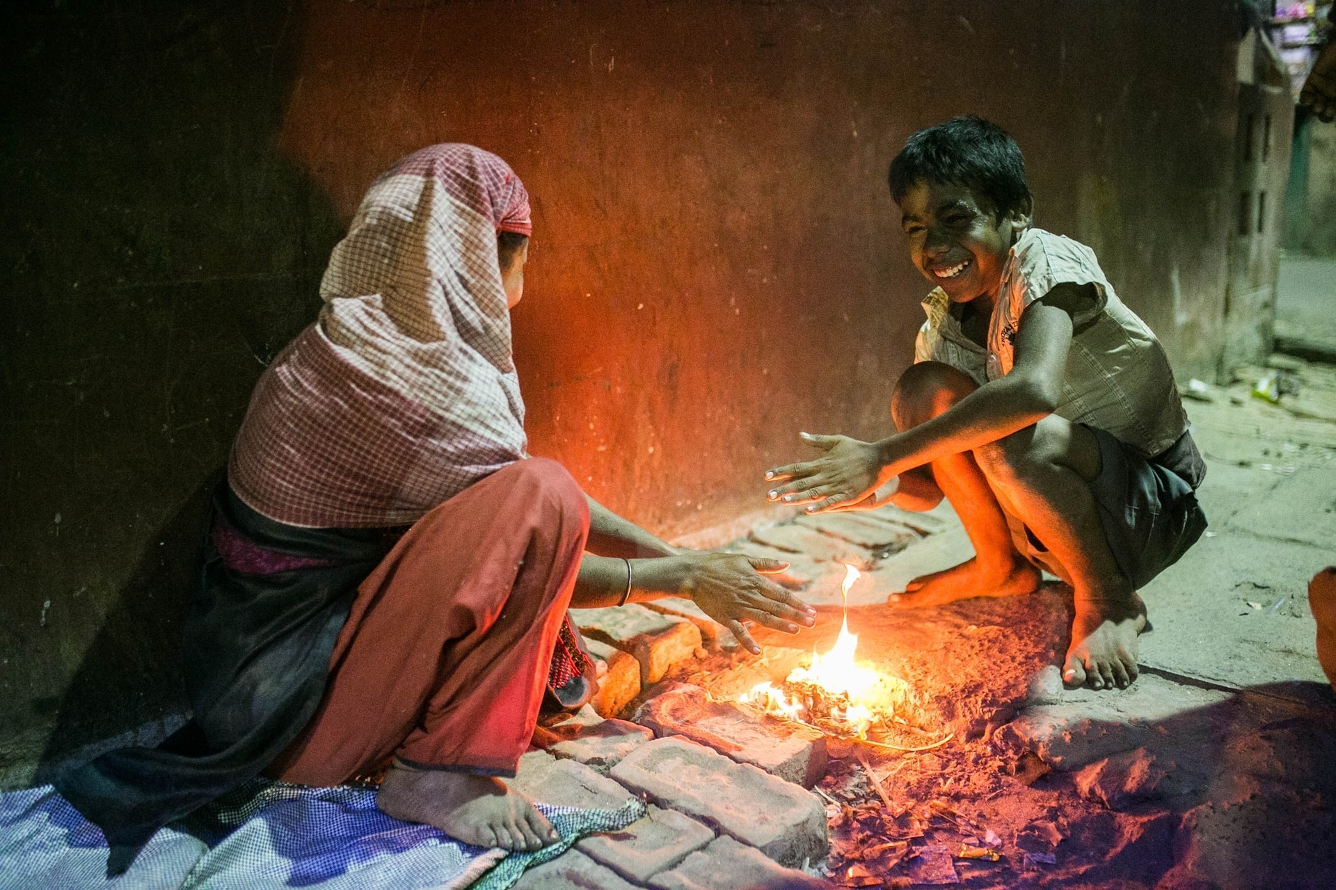 En kvinne og et barn lager mat over et bål