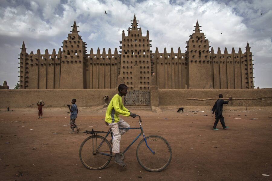 En gutt sykler forbi "the Great Mosque of Djenné", som sammen med gamlebyen i Djenné, har vært på Verdensarvlisten siden 1988.