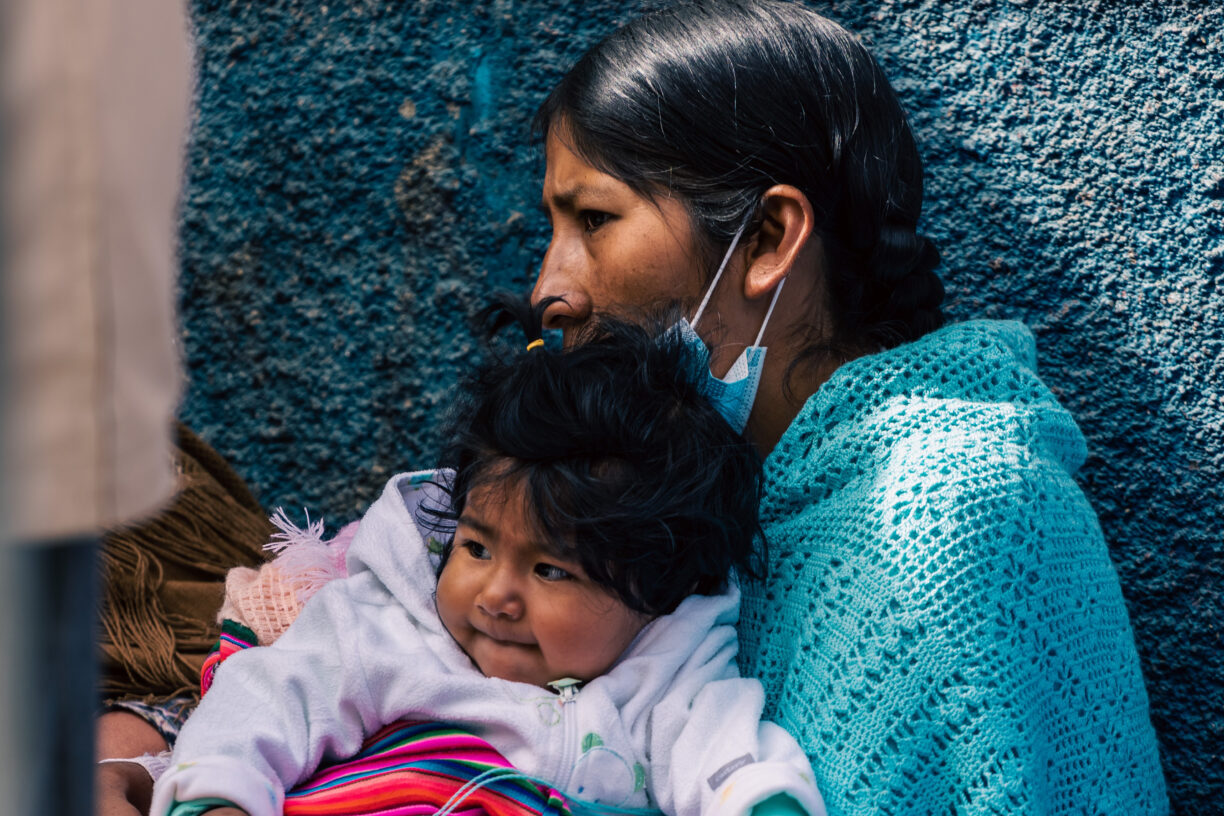 En kvinne i Bolivia venter i kø for å få mat, sammen med barnet sitt. Foto: Jack Prommel/Unsplash