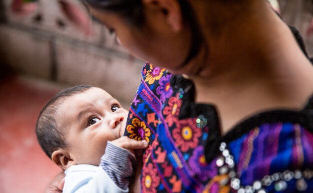 Eva Ramírez ammer sønnen sin, Junior Chales Ramírez, som er seksten måneder gammel. De bor i Chicoy, Huehuetenango, Guatemala. Amming bekjemper feilernæring og beskytter helsen til mor og barn. Amming fremmer også sunn vekst og den beste mulige utviklingen i tidlig barndom.