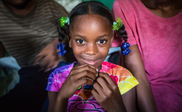 Ett tilfelle av kolera er bekreftet i Haitis hovedstad. En ung pike smiler til kamera på et bakeri i Port-Au-Prince.