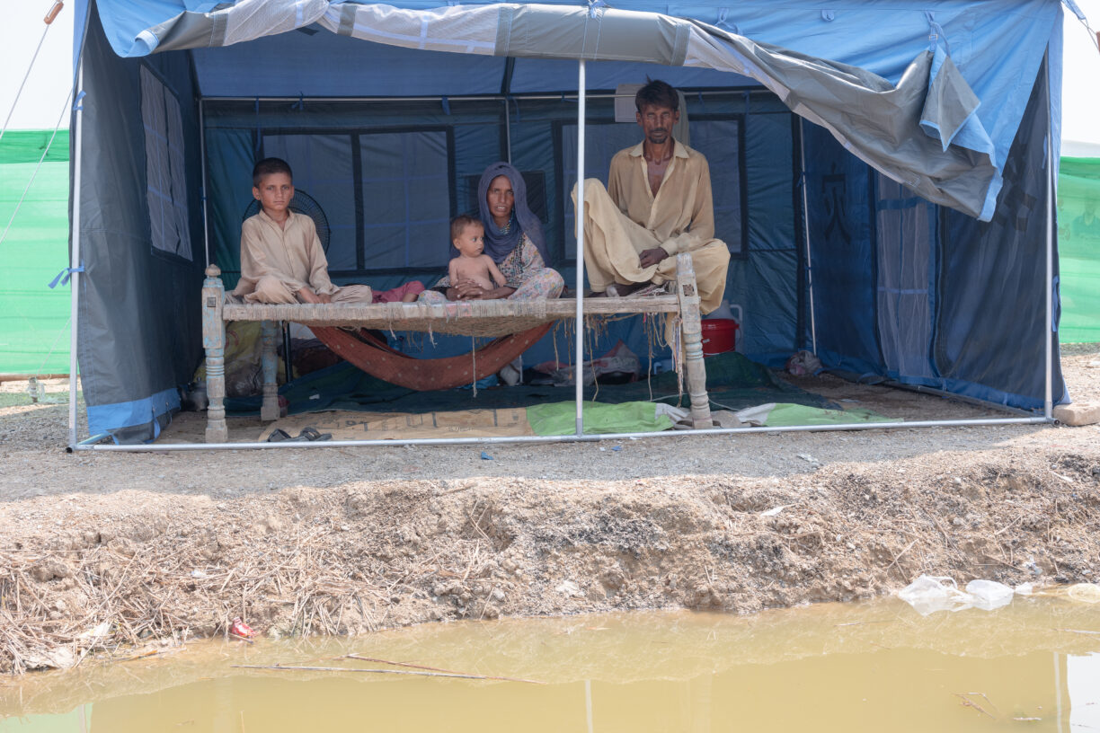 14. september 2022 poserer Hassan og Nazira Khan med deres 6 måneder gamle sønn Naqibullah (i Naziras fang), 18 måneder gamle Shoaib (liggende) og 8 år gamle Nasir Ahmed for et portrett i teltet der de bor, siden de ble fordrevet på grunn av flommene i Jaffarabad, et distrikt som nå er under vann i den sørvestlige provinsen Balochistan i Pakistan. Familien måtte redde seg selv da vannet kom og måtte flykte, uten noen av tingene sine. Foto: UNICEF/ UN0712729/d'Aki