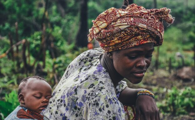 En mor bærer barnet sitt i Sierra Leone.