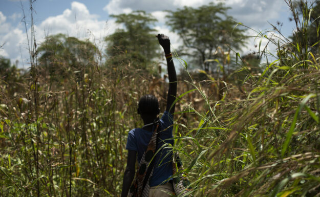 En 13 år gammel jente står midt i en åker i Uganda.