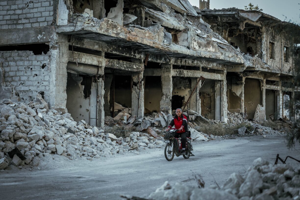 En mann kjører gjennom ødelagte gater i Syria. Krigen i landet har også svekket landets beredskap mot naturkatastrofer. Foto: Mahmoud Sulaiman/Unsplash.