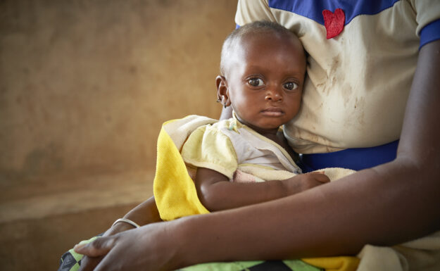 Zourata Sawadogo holder babyen sin, som lider av alvorlig akutt underernæring, på barneavdelingen ved Barsalogho medisinske senter i Burkina Faso. Foto: OCHA/Bénédicte Bienzi Toé.