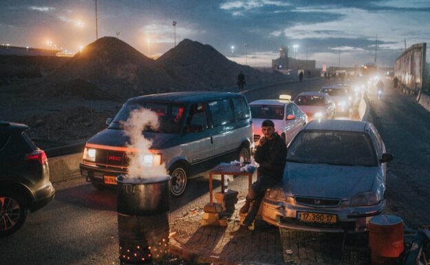 En mann venter ved en lang bilkø mot et grensekontrollpunkt fra Ramallah, Palestina inn i Israel. Foto: Cole Keister/Unsplash.