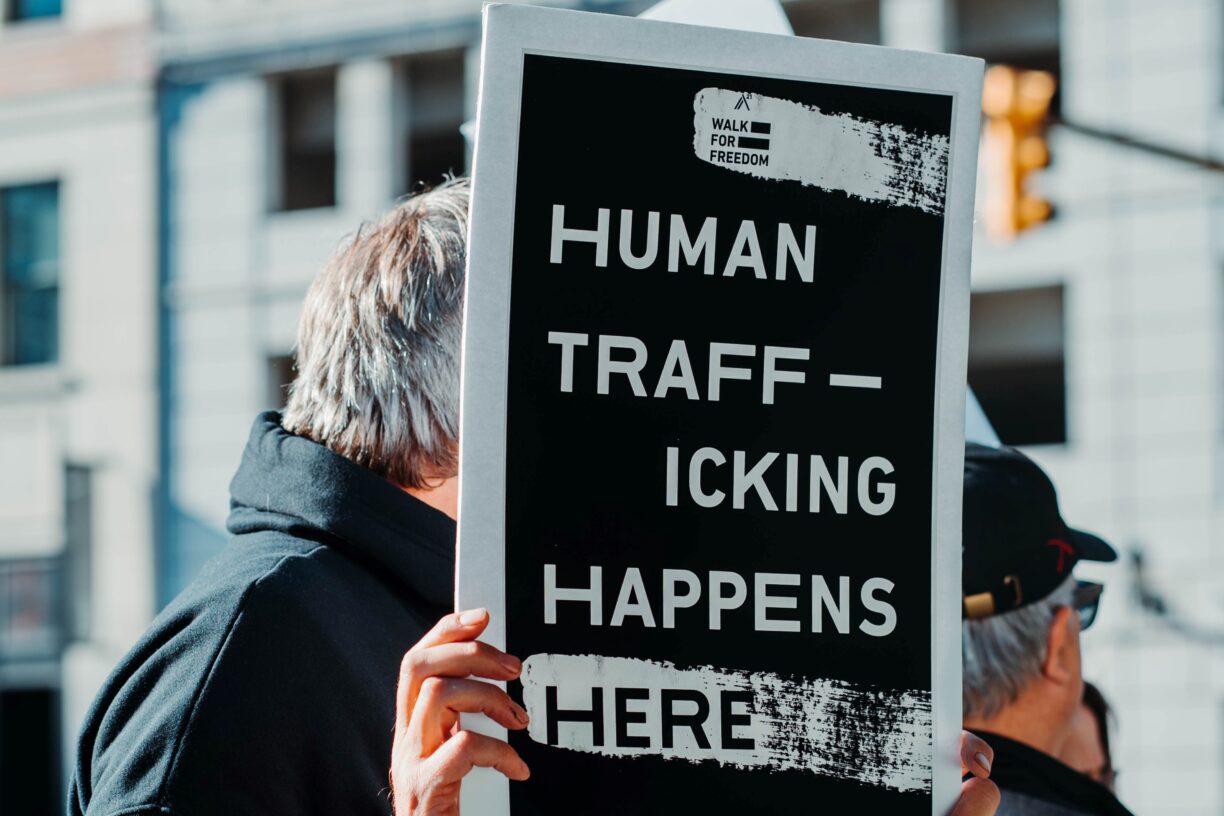 Antall ofre for menneskehandel som ble oppdaget rundt om i verden falt i 2020 med 11 prosent fra året før, ifølge en ny UNODC -rapport. Her står en mann med et skilt hvor det står: «Human trafficking happens here», eller «Menneskehandel skjer her» for å sette fokus på menneskehandel som et globalt problem i dag. Foto: Hermes Rivera/Unsplash.
