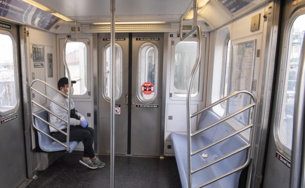 En enslig passasjer med maske og hansker på t-banen i New York, under koronapandemien . Foto: UN-photo/Evan Schneider