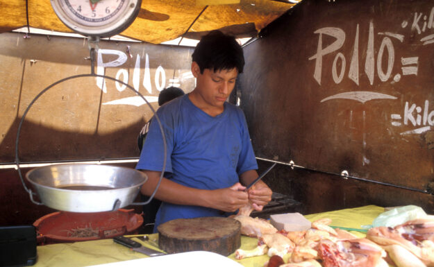 Nedgangstidene merkes over hele Latin-Amerika. Her forbereder en selger mat på et marked i Lima, Peru. Foto: ILO/Lord R.