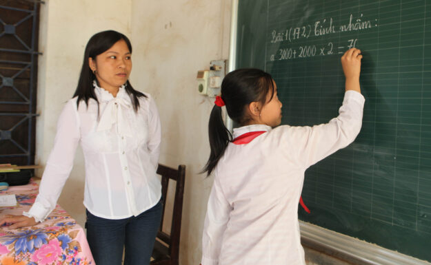 En lærer og eleven hennes løser mattestykker på en skole i Vietnam. Foto: ILO/Truong Van Vi