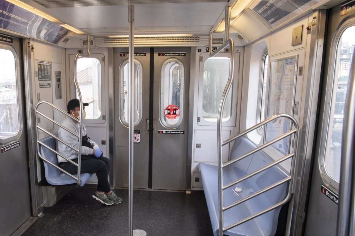 En enslig passasjer med maske og hansker på t-banen i New York, under koronapandemien. Foto: UN Photo/Evan Schneider